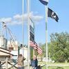 Trent Brewer, left, and Kim Lang raise the ­American flag.